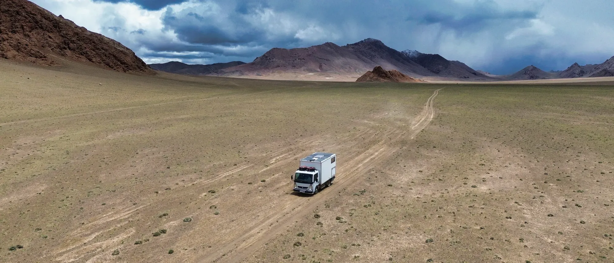 一辆露营车行驶在塔吉克斯坦帕米尔高原的高山之间